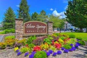 Exterior front entrance signage, meticulous landscaping, lush foliage, residential buildings in background.