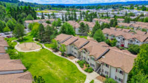 Aerial Exterior, residential buildings, playscape between buildings, meticulous landscaping, view of surrounding communities in the background.