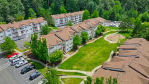 Aerial Exterior, residential buildings, playscape between buildings, meticulous landscaping, trees planted along sidewalks, parking out front.
